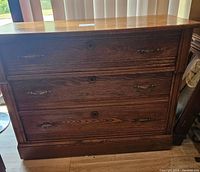 Front view of oak dresser showing three drawers with brass handles and keyholes.