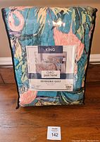 Photo of the packed comforter in original packaging showing colorful floral pattern including blue and orange hues with palm leaf designs.