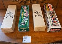 Photo of four boxes of baseball cards from the 1990s shown on wooden surface including labeled boxes and branded Donruss box.