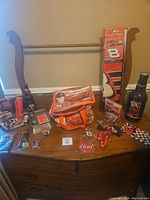Overview photo showing multiple Dale Earnhardt Jr #8 collectibles spread out on a wooden surface including keychains, wallets, tins, novelty bottles, coasters, and memorabilia boxes.