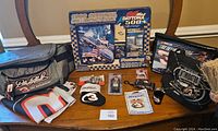 Overview of lot featuring Dale Earnhardt cooler bags, Daytona 500 puzzle box, collectibles, and flag folded on table