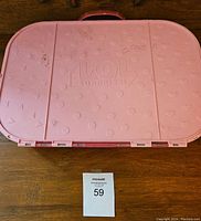 Closed pink plastic LOL Surprise carrying case with embossed logo on lid, showing minor scuffs.