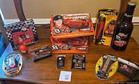 Wide view of all items in the lot including diecast cars, photo frame, branded batteries, playing cards, keychain, and bottle