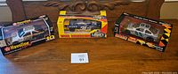 Photo showing all three diecast NASCAR cars in original packaging on wood surface