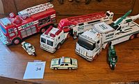 Lot of six Hess vehicles including fire trucks, ambulance, patrol car, and two motorcycles displayed on a wooden surface.