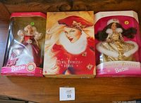 Three Barbie dolls in original boxes placed side by side on a wooden surface. The dolls are Special Edition Barbie, Jewel Princess Barbie, and Winter Fantasy Barbie.