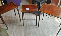 Overview of the three brown wooden nesting tables arranged on a light wooden floor.