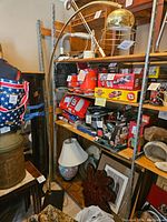 Full view of the retro brass arc floor lamp set among other items on shelving, showing its curved arm and brass construction.