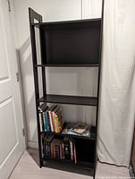 Lower shelves of the black Ikea LAIVA bookshelf holding a variety of books