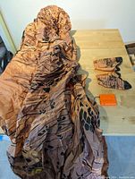 Inflatable T-Rex costume laid out showing fabric with dinosaur print, gloves and battery pack on table