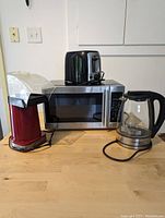 Red Cuisinart Easypop popcorn maker, black Black & Decker toaster, Hamilton Beach glass electric kettle, and Hamilton Beach microwave on counter.