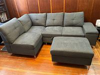 Full view of left-facing sectional with ottoman in charcoal fabric