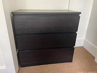 Front left angle view of the black-brown Ikea MALM 3-drawer dresser showing smooth drawer fronts and real wood veneer finish.