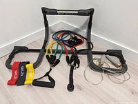 Pull-up bar with attached multi-color resistance bands, showing foam padding damage and included accessories like jump rope and additional bands.