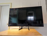 Front view of TV on wooden table showing screen and bezel
