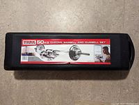 Closed black hard plastic case with York 50 kg chrome barbell and dumbbell set label
