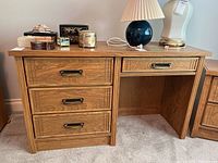 Front view of wood desk showing four drawers and metal handles.