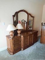 Front view of dresser with mirror, two tabletop lamps placed on top.