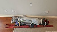 Full lot showing grey golf bag with clubs, red ski poles and black/red ski boots.