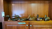 Five carved wooden duck decoys displayed side by side on shelf