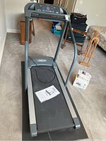 Front view of Pacemaster Bronze Basic treadmill showing control panel and running belt with owner's manual on it.