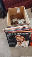 Box with LP vinyl records and CDs inside. The Kenny Rogers Greatest Hits LP is prominently visible.