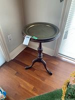 Full side view of the wood side table with metal tray insert showing the turned pedestal and tripod base on wood flooring.