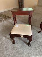 Photo showing wood side table and plastic-covered cushioned footstool on carpet, highlighting size and condition