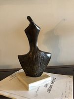 Front view of bronze abstract sculpture on stone base against neutral wall