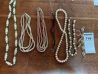 Full lot showing pearl necklaces, a black cord pendant necklace, a gold-tone bracelet and matching earrings.