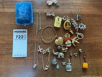 Photo of the majority of costume jewelry items spread on table, including necklaces, pins, earrings, pendants and blue velvet jewelry case.