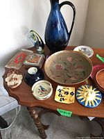 Overview of decor items including Moorcroft bowl, vase, coasters, plates, and other decorative pieces on wooden table.