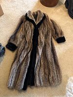 Full front view of the ladies full-length fur coat with contrasting dark trim on cuffs and interior edges.