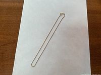 Full view of gold box link chain laid flat on white background