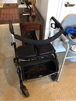 Side view of Evolution Trillium 6 walker showing padded seat, black storage pouch underneath, and handles with loop brakes