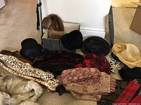 Overview photo of various ladies hats, scarf, and fur stoles laid on floor showing multiple styles and patterns.