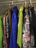 View of assorted jackets and sweaters on hangers, showing varied colors and patterns including bright chartreuse, blue and multi-color prints.