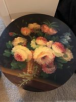 Top view of largest round nesting box lid showing floral basket painting on black background
