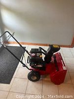 Red Yard Machines 22 inch 2-stage self-propelled snow blower angled side view on tile floor.