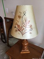 Full view of wooden base table lamp with beige Dornbusch shade showing floral design.