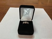 Three-stone diamond ring displayed in black velvet presentation box on white background