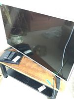 42 inch LG flat screen TV with remote and cords on wooden table.