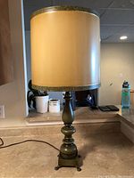 Table lamp with turned wood green crackle finish base and antiqued paper shade with green trim.