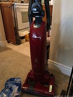 Full front view of red Panasonic upright vacuum cleaner with hose and branding visible.