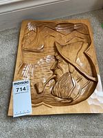 Photo showing full view of the carved wooden artwork with sailor profile, waves, mountains, and pipe in scene.
