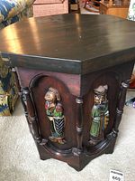 Side view of dark wood octagonal table showing carved and painted knight figure in relief with turned column.