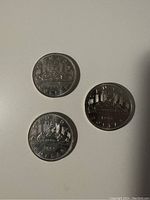 Reverse side of three Canadian dollar coins showing the Voyageur canoe design with dates 1967, 1968, and 1969.