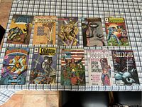 Full array of 10 sealed comic books laid flat on a plaid surface showing cover artwork and titles including The Savage Dragon, Godland, Shadowhawk and Wildcats.