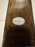 Close-up of metal plaque on wooden metronome showing brand Maelzel Paquet and date 1846 Made in France.