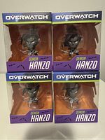 Four Overwatch Demon Hanzo figurines in sealed original packaging arranged in a 2x2 grid, showing the front of each box with branding and character details.